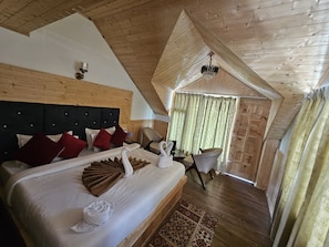 A hotel room with a large bed, wooden ceiling, and a view of the outside. - Hotel Apple Resort Sangla (Sangla)