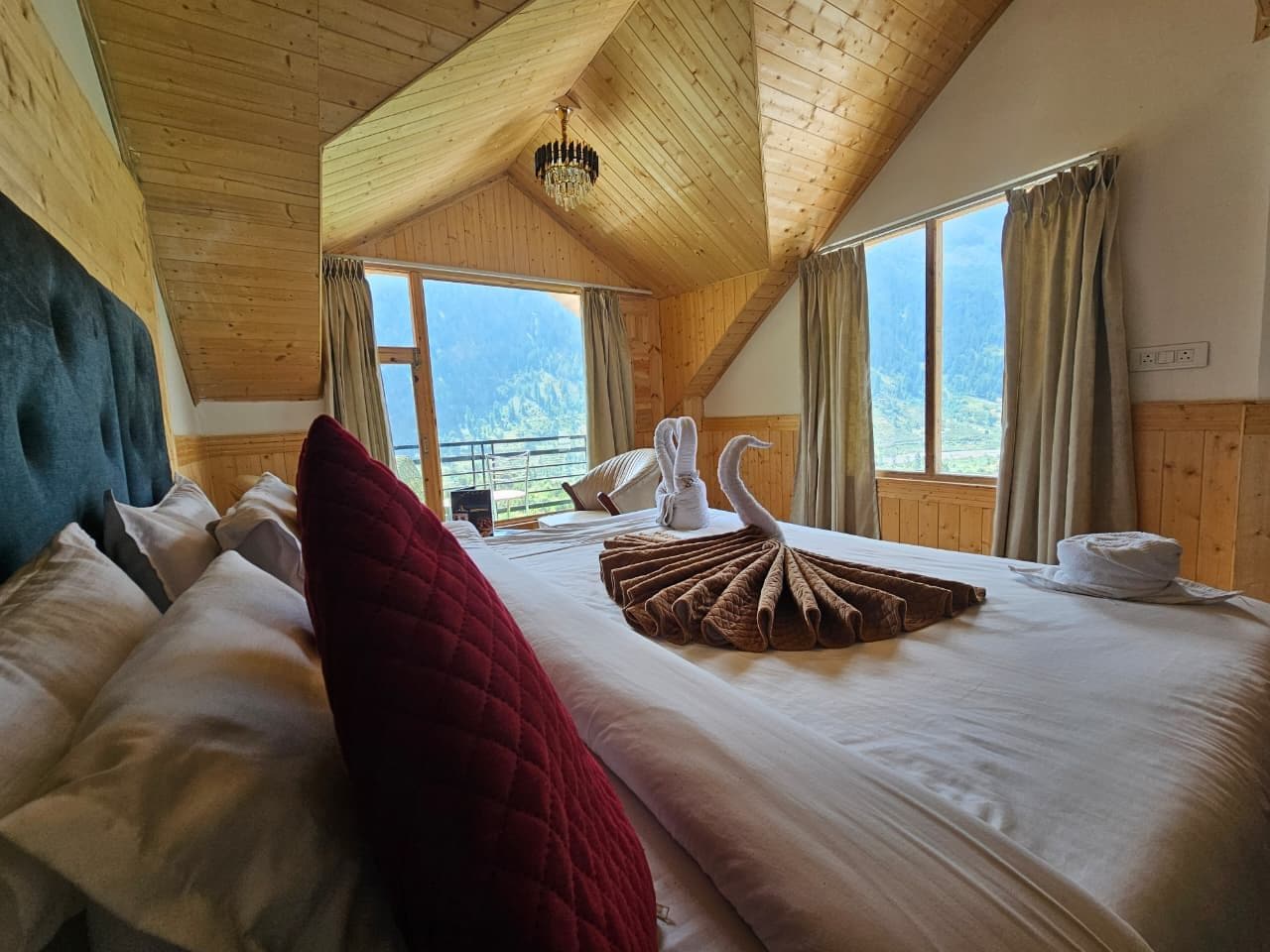 Ein Schlafzimmer mit einem großen Bett, Holzboden und Blick auf Berge durch das Fenster.