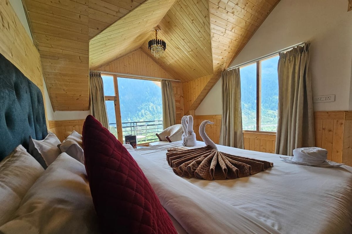 A bedroom with a large bed, wooden ceiling, and a view of mountains through the window.