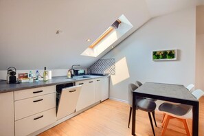 Eine moderne Küche mit Dachfenster, einem Essbereich mit Tisch und Stühlen sowie einer Muster-Spritzschutzwand.
