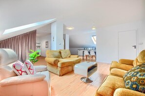 Ein modernes Wohnzimmer mit einer Couch, einem Couchtisch und einem Essbereich mit Stühlen.