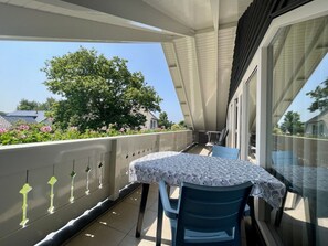 A balcony with a table and chairs, a view of a tree, and a building in the background. - Prinsepark 1st Floor (Domburg)