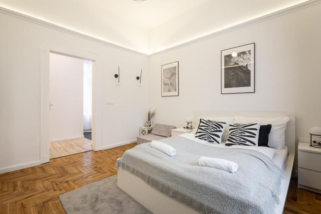 Un dormitorio con una cama grande, una mesita de noche, una lámpara de pared y dos apliques.