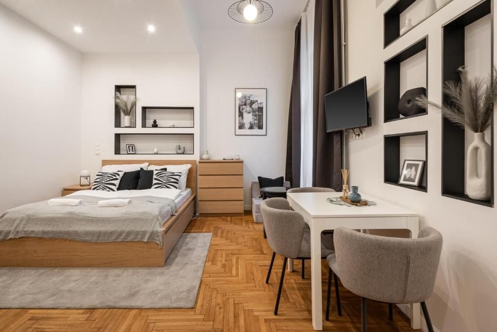A modern bedroom with a bed, bedside table, and a desk with chairs.