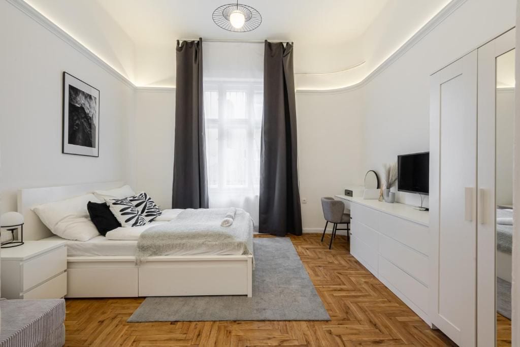 Un dormitorio moderno con una cama, mesita de noche y un escritorio con silla.