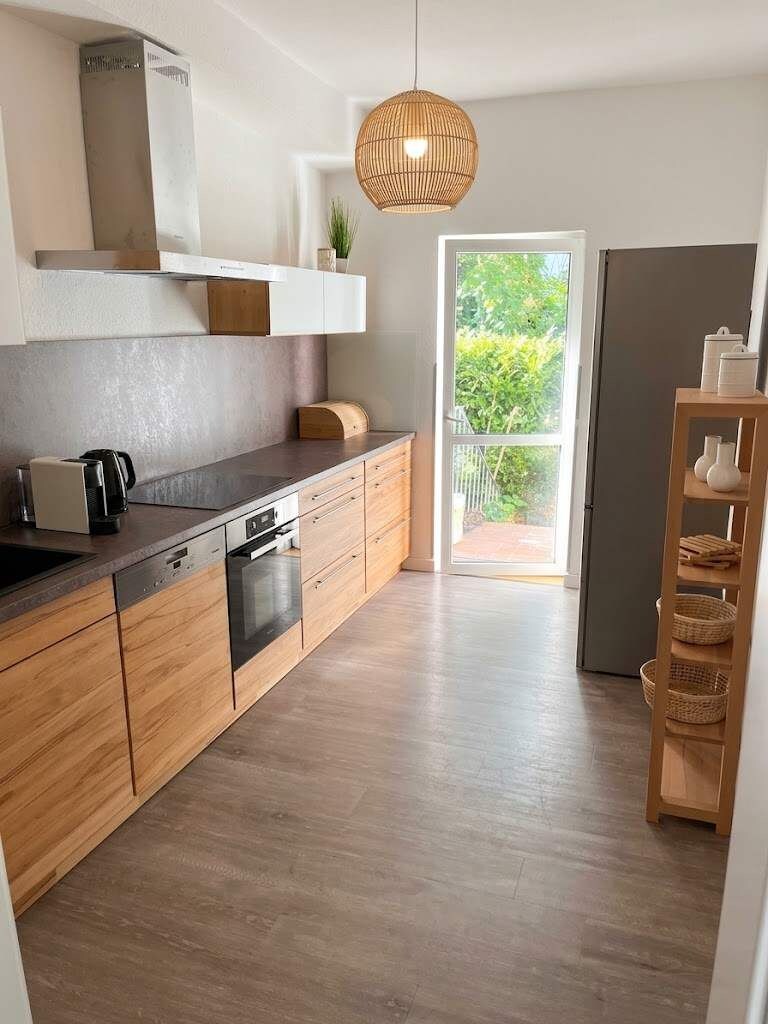 Una cocina moderna con armarios de madera, horno empotrado y un amplio ventanal.