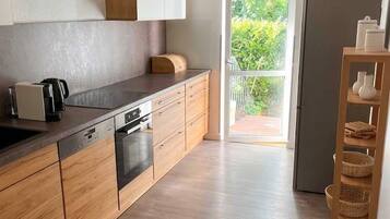 Una cocina moderna con armarios de madera, horno empotrado y un amplio ventanal.