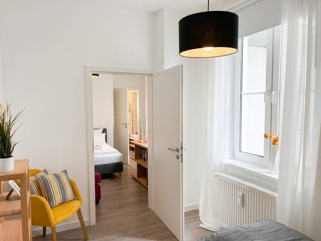 A modern bedroom with a bed, bedside table, and a window with curtains.