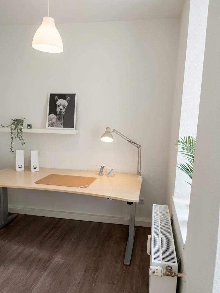 Ein moderner Schreibtisch mit einer Lampe, einem gerahmten Bild und einer Heizung.