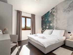 Ein modernes Schlafzimmer mit einem großen Bett, einem Schreibtisch und einem Fenster mit Vorhängen.