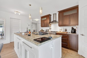 A modern kitchen with a central island, stainless steel appliances, and wooden cabinetry. - L'Écrin: Contemporary elegance and cozy comfort in the heart of the city. (Québec)