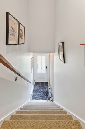 A staircase with a patterned carpet leading to a door with a frosted glass panel. - L'Écrin: Contemporary elegance and cozy comfort in the heart of the city. (Québec)