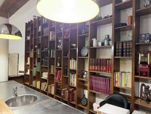 A library with bookshelves, a desk, a sink, and a clock.