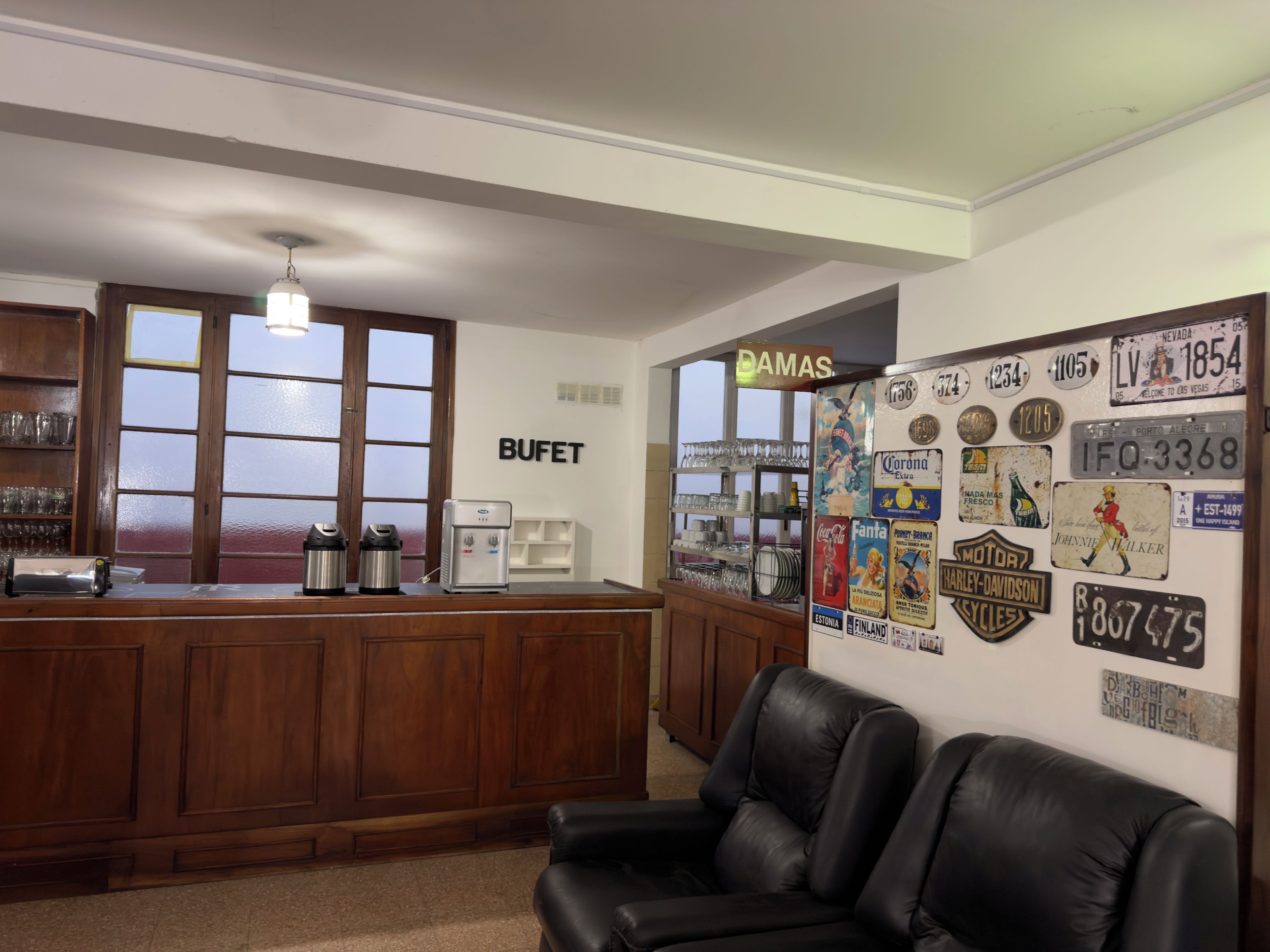 Un espace bar avec un comptoir, des sièges et un mur décoré de plaques d’immatriculation et d’objets de collection.