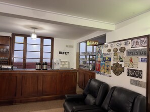 A bar area with a counter, seating, and a wall decorated with license plates and memorabilia.