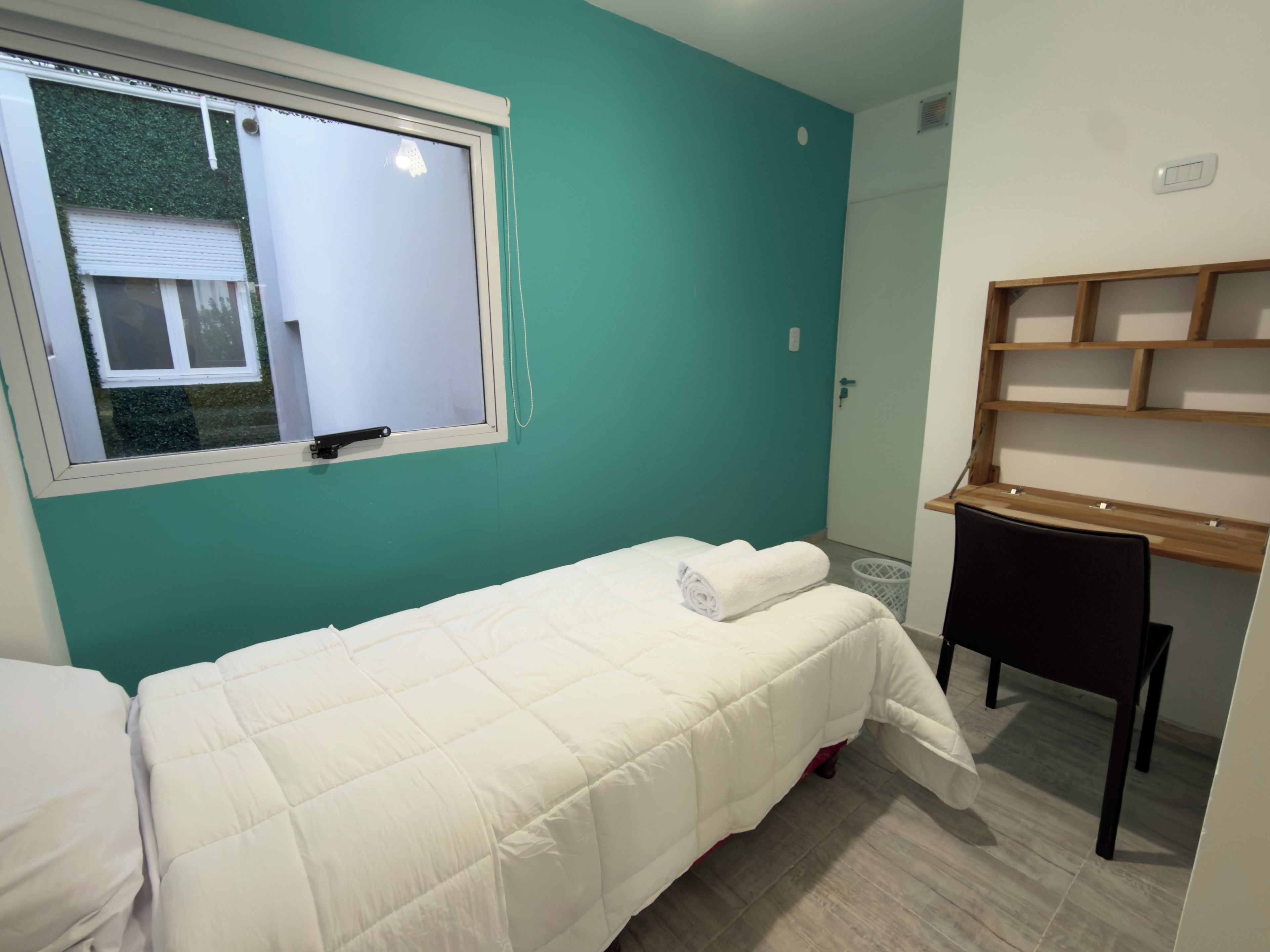 Habitació individual amb un llit, una finestra, un escriptori i una cadira.