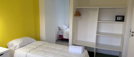 A hotel room with a bed, a white wardrobe, and a small desk.