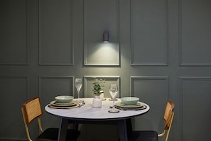 A dining table with a white tablecloth, two chairs, a vase with a plant, and two wine glasses. - Host Stay - The Enterprise Suite (Middlesbrough)