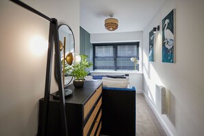 A hallway with a mirror, a potted plant, a bed, and artwork on the walls. - Host Stay - The Enterprise Suite (Middlesbrough)