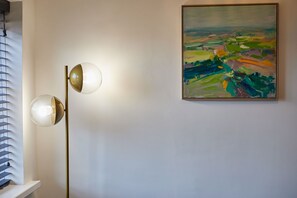 A modern floor lamp with two spherical shades and a colorful abstract painting on the wall. - Host Stay - The Enterprise Suite (Middlesbrough)