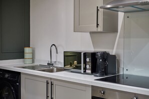 A modern kitchen with a built-in dishwasher, a coffee machine, and a microwave. - Host Stay - The Enterprise Suite (Middlesbrough)