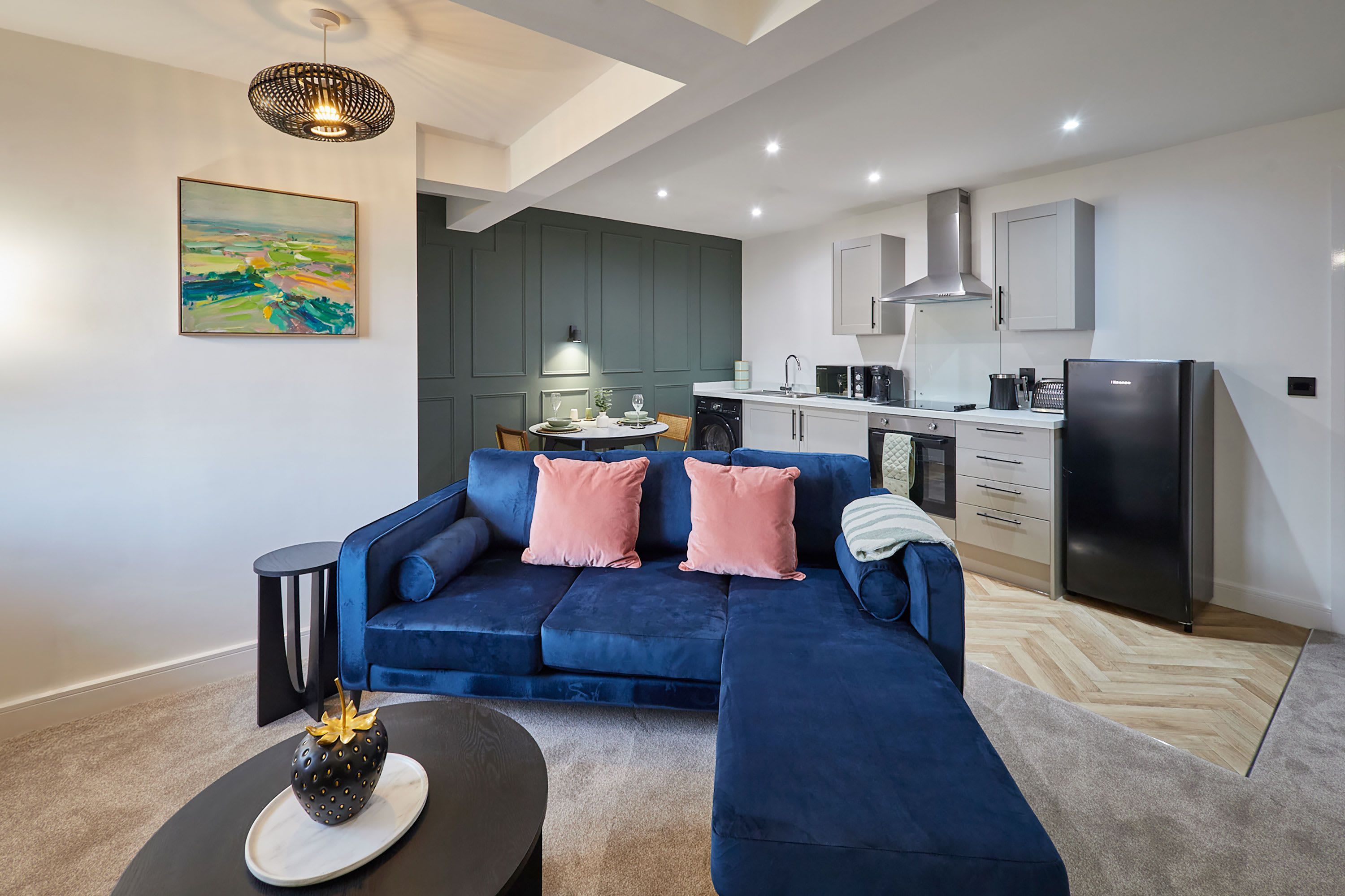 Un salon moderne avec un canapé bleu, une table basse et un tableau accroché au mur.