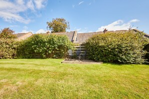 A garden with a bench and a small table, surrounded by well-maintained hedges and a grassy lawn. - Host and Stay - The Cottage ALN (Alnwick)