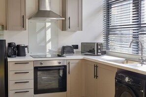 A modern kitchen with a built-in oven, a coffee maker, a toaster, and a dishwasher. - Host Stay - The Premier Loft (Middlesbrough)