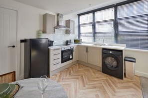 A compact kitchen with a refrigerator, microwave, sink, and washing machine. - Host Stay - The Premier Loft (Middlesbrough)
