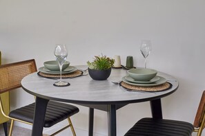 A round dining table with two chairs, a potted plant, and a candle. - Host Stay - The Premier Loft (Middlesbrough)