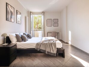 A modern bedroom with a large bed, bedside tables, a desk, and a view of the outdoors. - Casa Michela - 20 Minutes to the City Center (Scandicci)