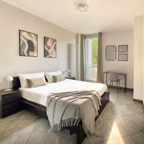A modern bedroom with a large bed, bedside tables, a desk, and chairs. - Casa Michela - 20 Minutes to the City Center (Scandicci)