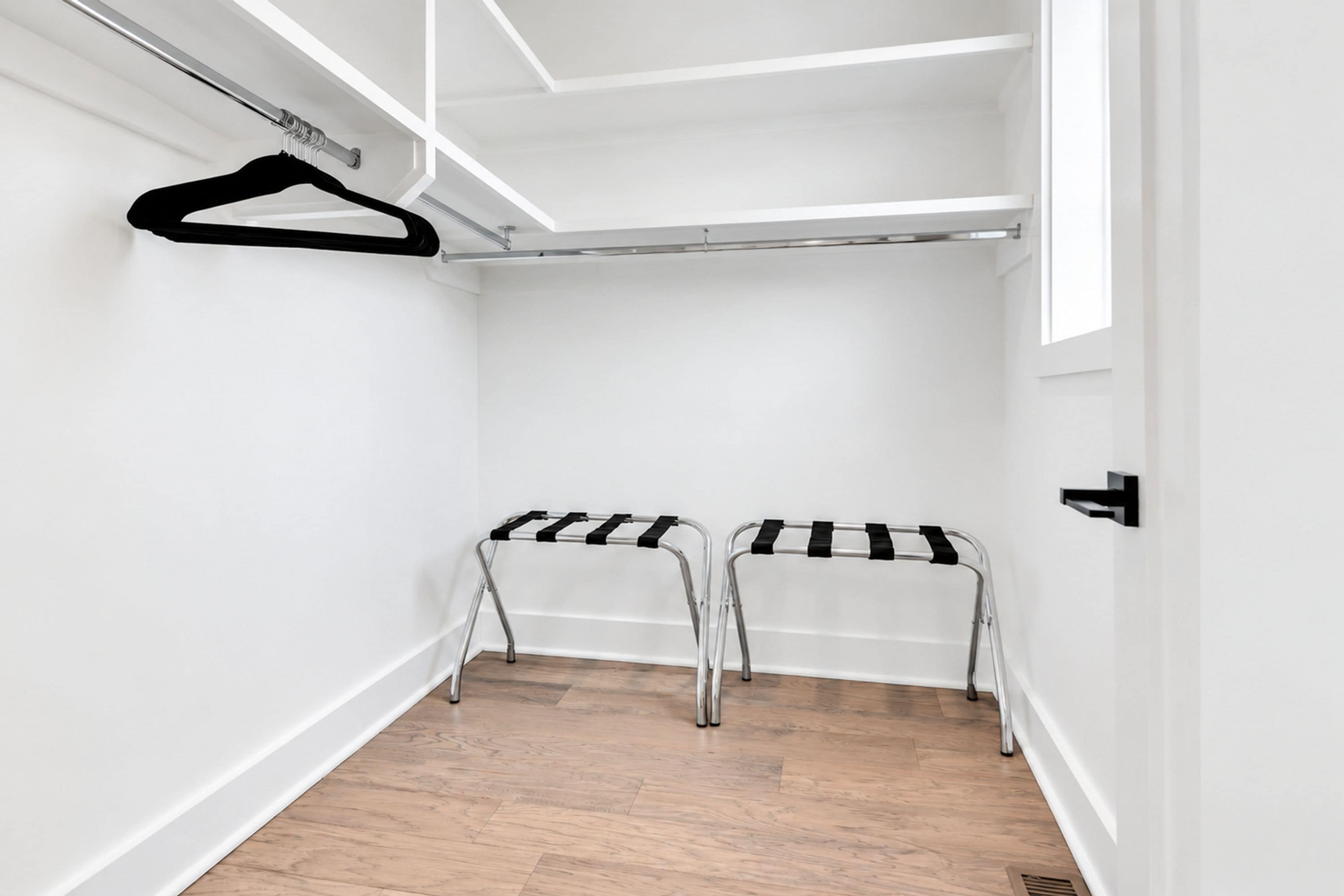 A walk-in closet with two metal drying racks and a white door.