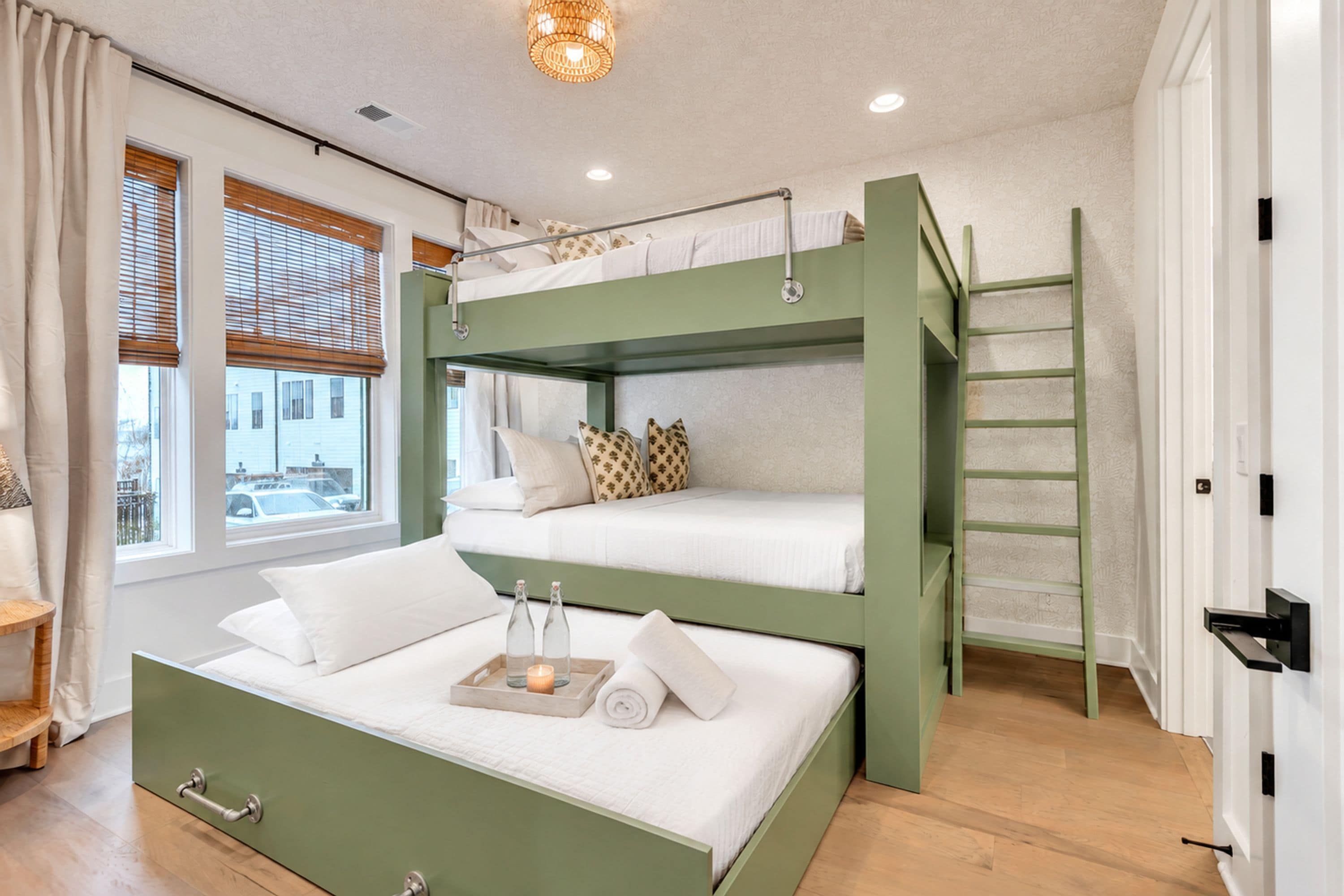 A bunk bed room with a window, a bedside table, and a view of the outside.