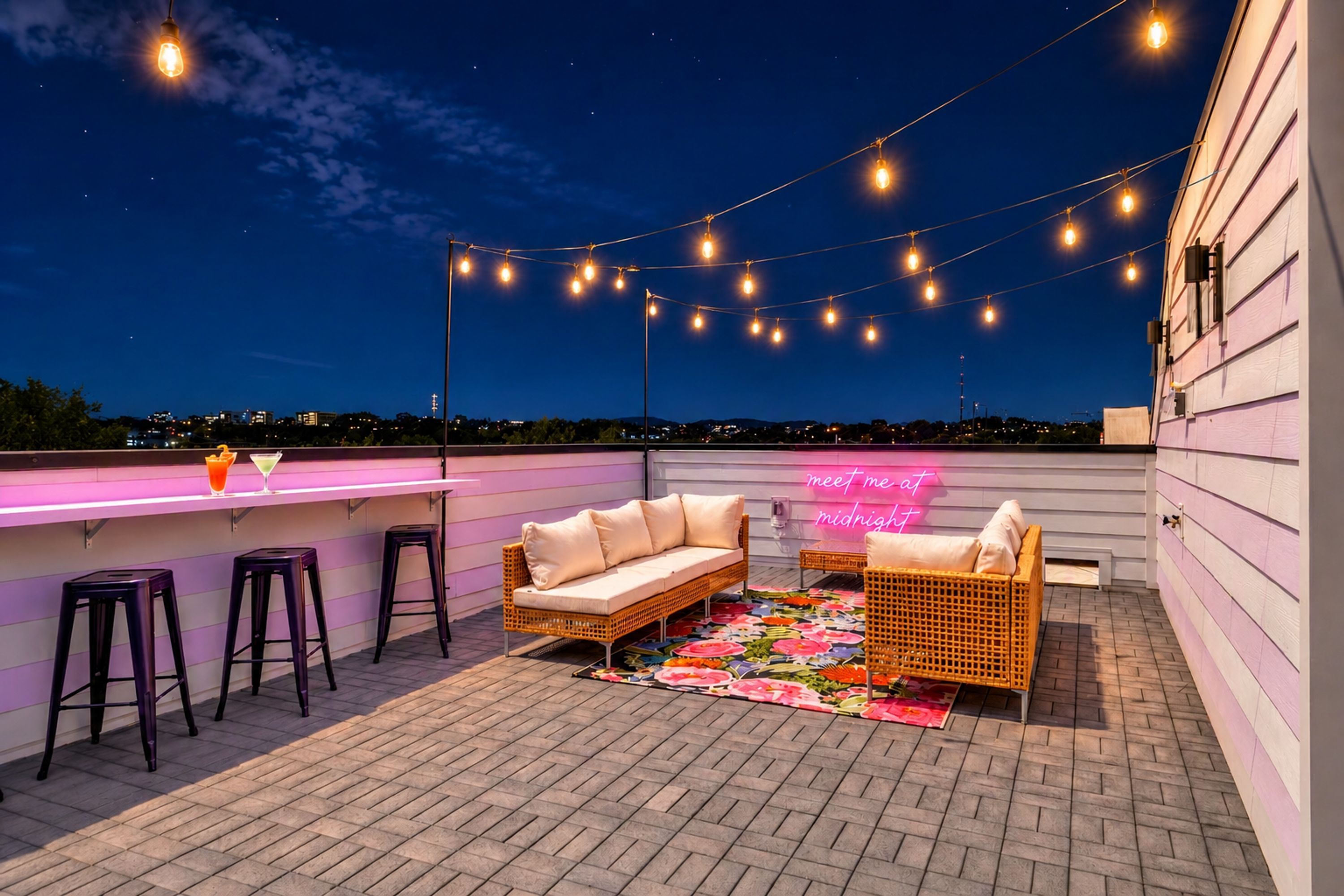 An outdoor patio with a bar area, seating, and string lights.
