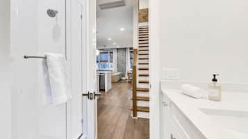A modern bathroom with a shower, a towel rack, and a sink with a soap dispenser.