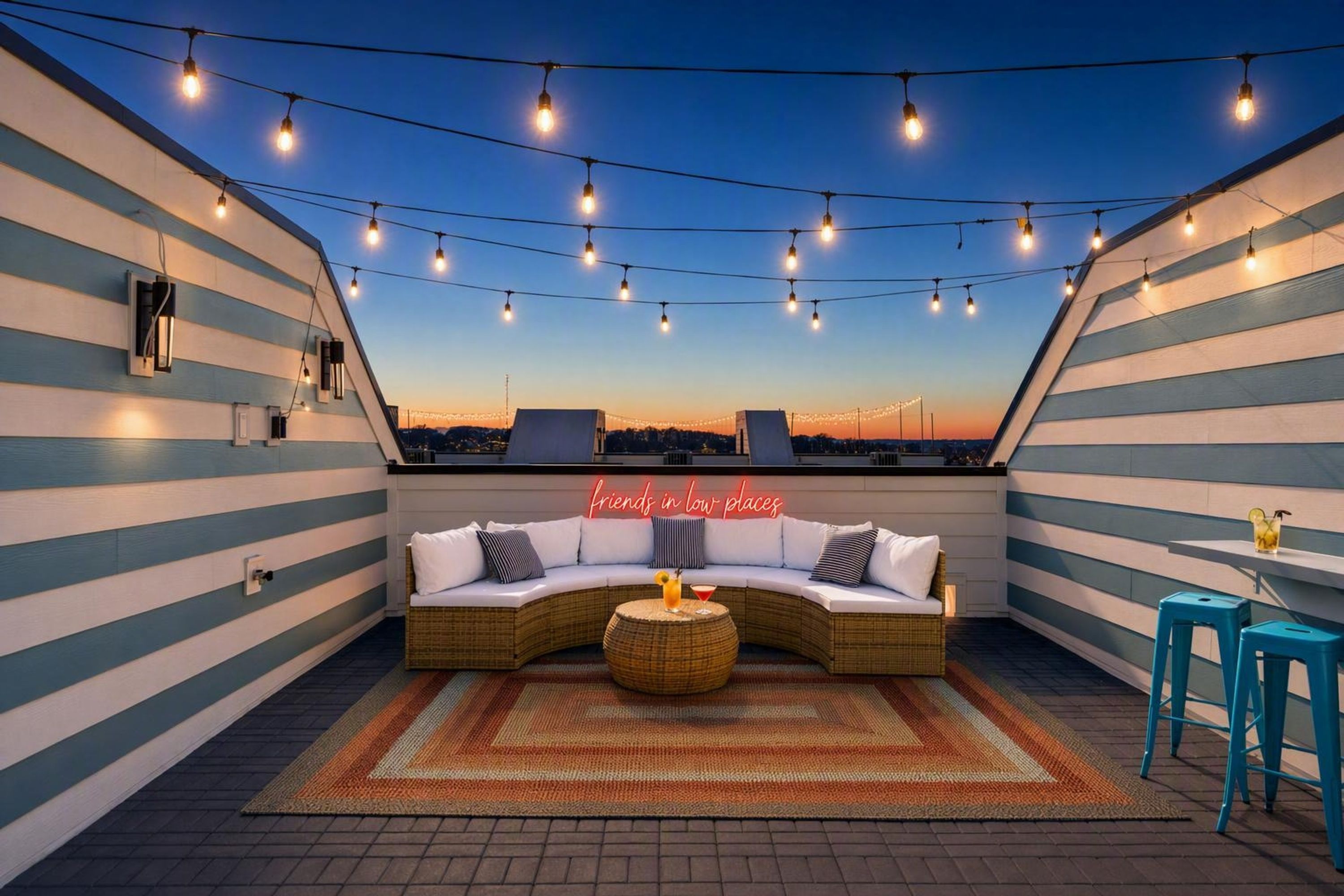 Eine Dachterrasse mit einer gebogenen Couch, einem runden Tisch und Lichterketten.
