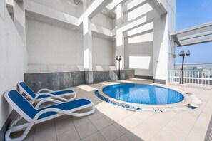 Ein Innenpool mit Liegestühlen und Fliesenboden.