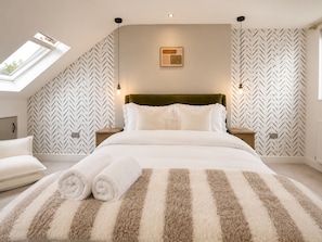 A bedroom with a herringbone-patterned wall, a green upholstered headboard, and a striped rug. - Perfect Booking Modern 4-bed Home With Garden (Windsor)