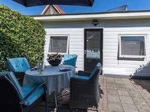 An outdoor patio with a round table, wicker chairs, and a potted plant. - Holiday Home in Renesse With Swimming Pool (Renesse)