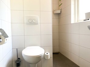 Ein Badezimmer mit Toilette, Bidet und Toilettenpapierhalterung.