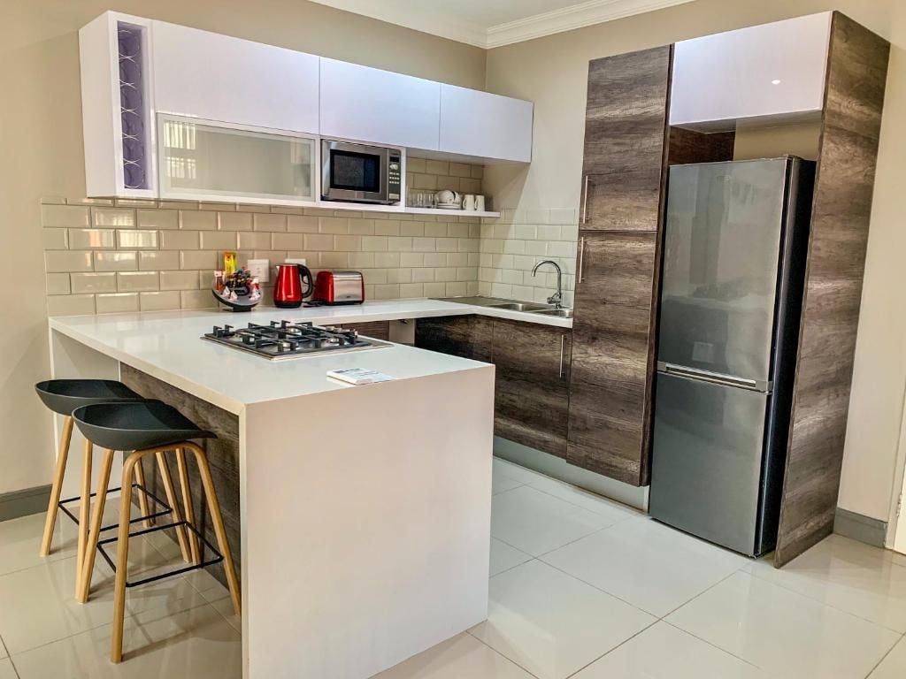 A modern kitchen with white cabinets, a stainless steel refrigerator, a microwave, and a gas stove.