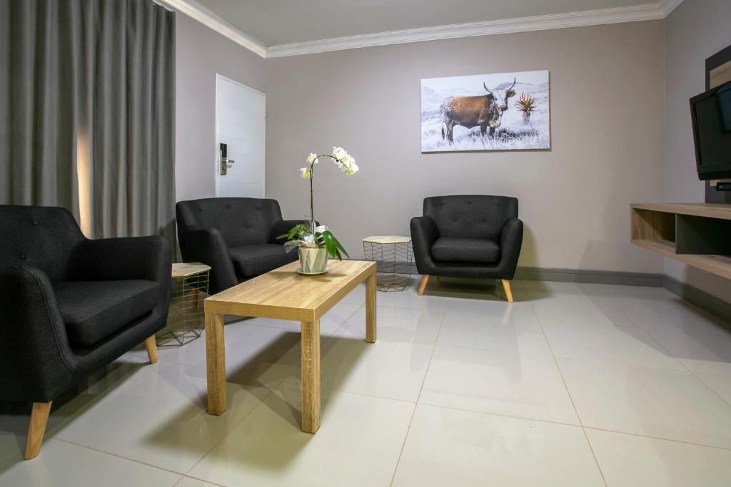 A modern living room with two black armchairs, a wooden coffee table, and a painting of a bull on the wall.