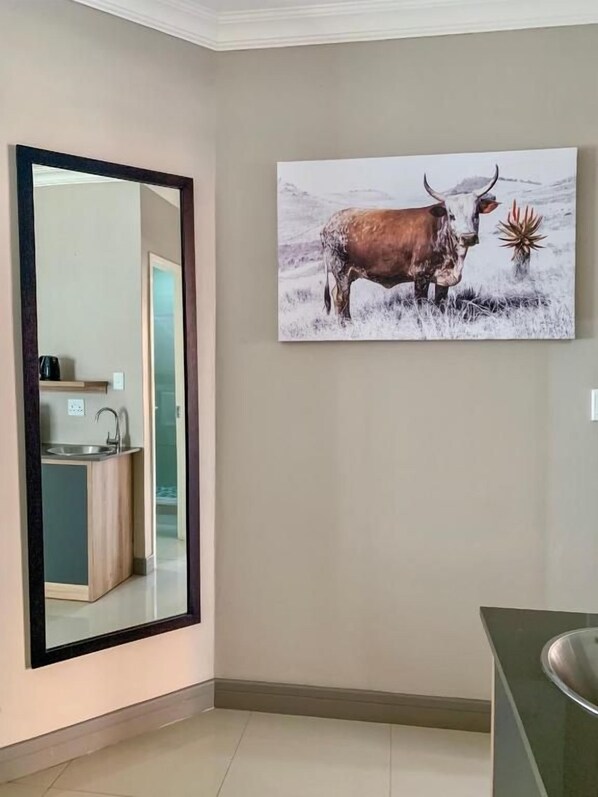 Ein Zimmer mit einem großen Spiegel, einem Gemälde eines Stiers und einem Waschbecken.