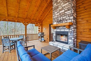 A covered outdoor area with a stone fireplace, seating, and a grill. - Sapphire Ridge Log Cabin~Hot Tub~Fire Pit~Hocking (Logan)