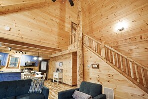 A wooden interior with a kitchen, dining area, and a staircase. - Sapphire Ridge Log Cabin~Hot Tub~Fire Pit~Hocking (Logan)
