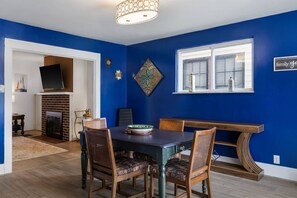 Ein Essbereich mit blauer Wand, Kamin und Fernseher im Hintergrund.