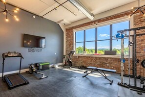 Ett gym med träningsutrustning, ett löpband, en motionscykel och ett stort fönster med utsikt.