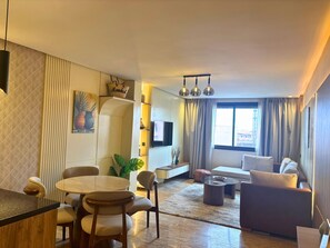 A modern living room with a sofa, a coffee table, and a dining area with chairs and a table. - Cozy Studio in Central Gueliz near Carre Eden (Marrakech)