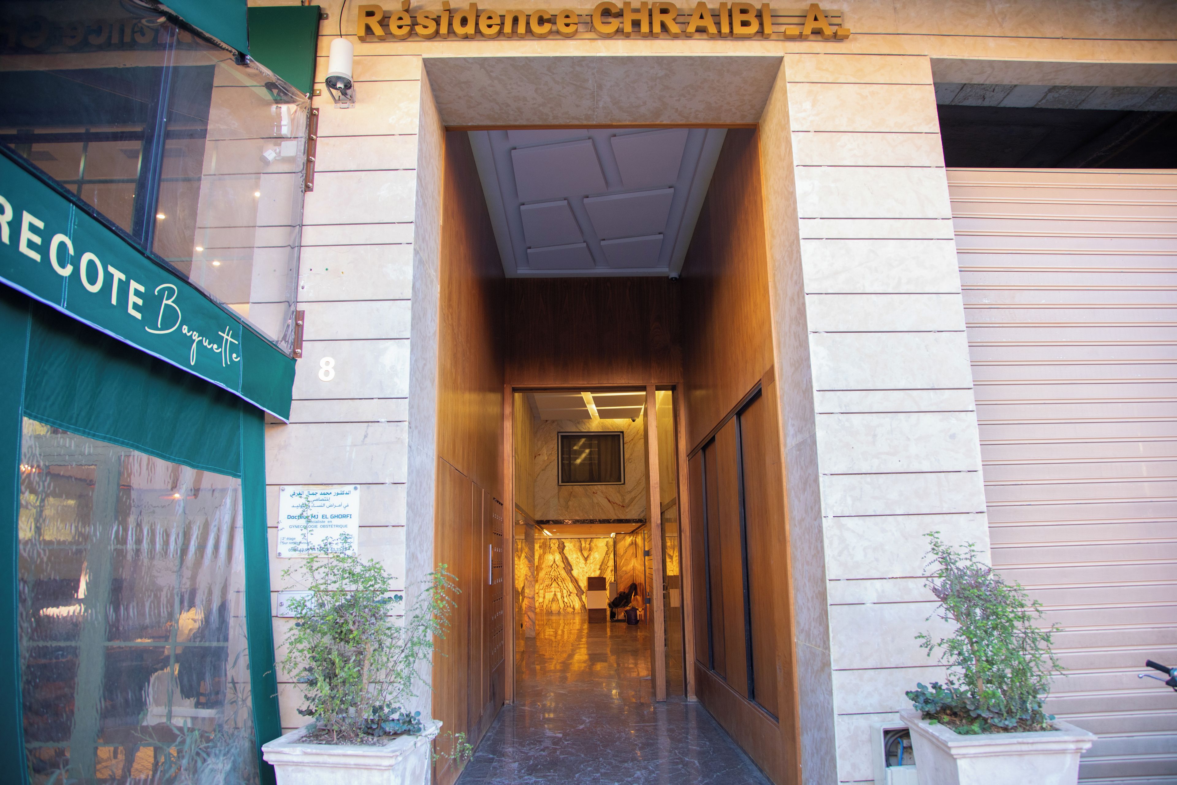 Entrada de hotel com uma placa indicando 'Residence Chraibi A'.